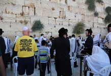 Judíos ultraortodoxos en el Muro de las Lamentaciones y un hombre con una camiseta que anuncia a Jesús como Puerta salvadora