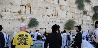 Judíos ultraortodoxos en el Muro de las Lamentaciones y un hombre con una camiseta que anuncia a Jesús como Puerta salvadora